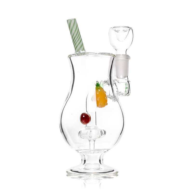 Vue de trois quarts du bang HEMPER Piña Colada avec ananas en verre, paille verte et blanche et socle transparent